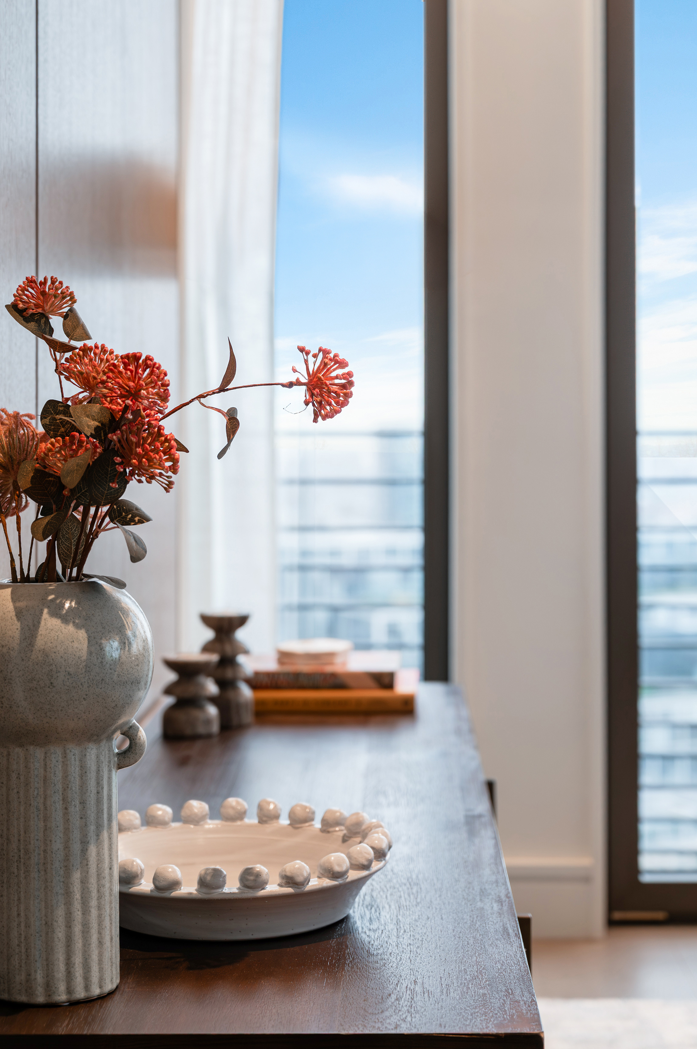 A styled console with flowers beside a residence window