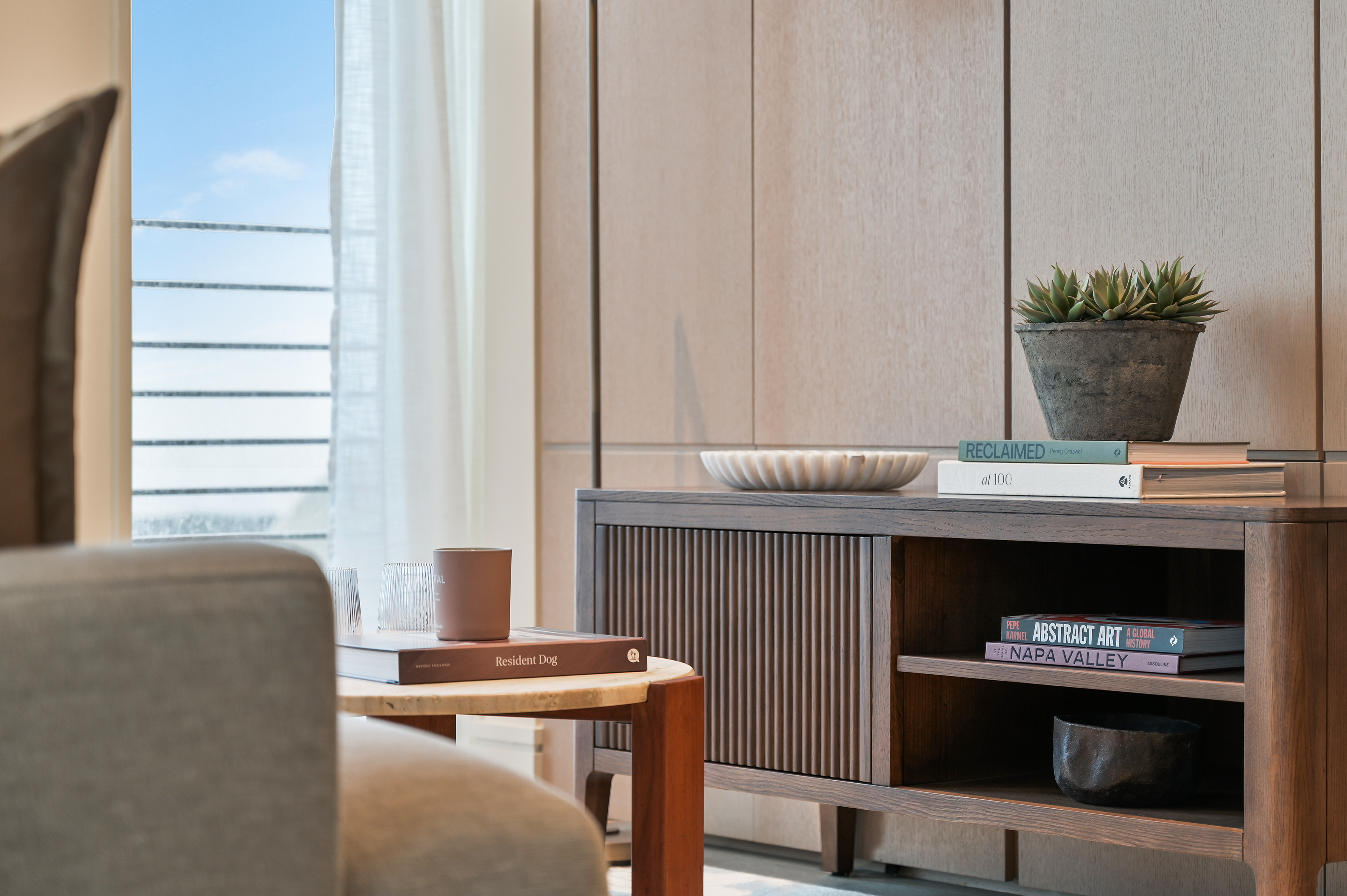 Styling detail of a living space — books and a candle on a side table